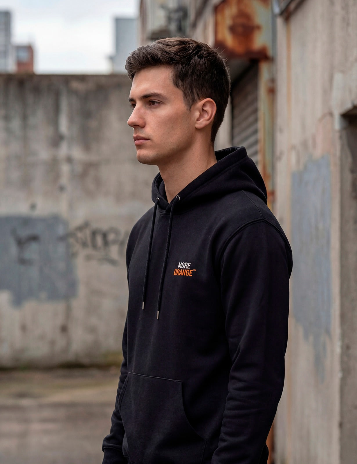 Side view of male model wearing black MORE ORANGE™ hoodie with minimalist branding