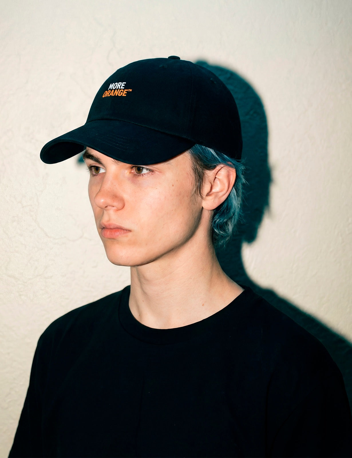 Young male model wearing black MORE ORANGE™ dad hat, front view, clean aesthetic