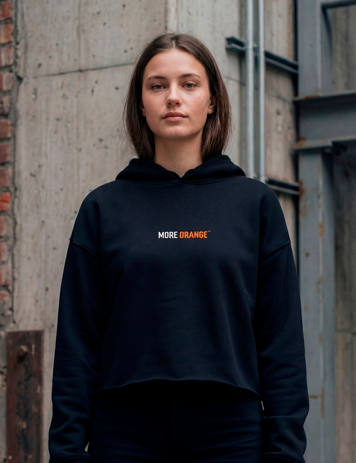 Front view of female model wearing black MORE ORANGE™ hoodie with subtle logo