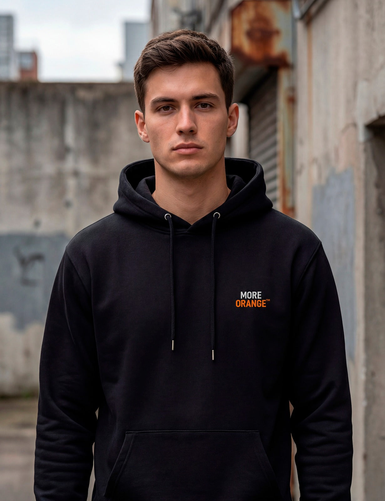 Front view of male model wearing black MORE ORANGE™ hoodie with subtle orange logo