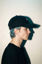 Side view of black MORE ORANGE™ dad hat worn by male model