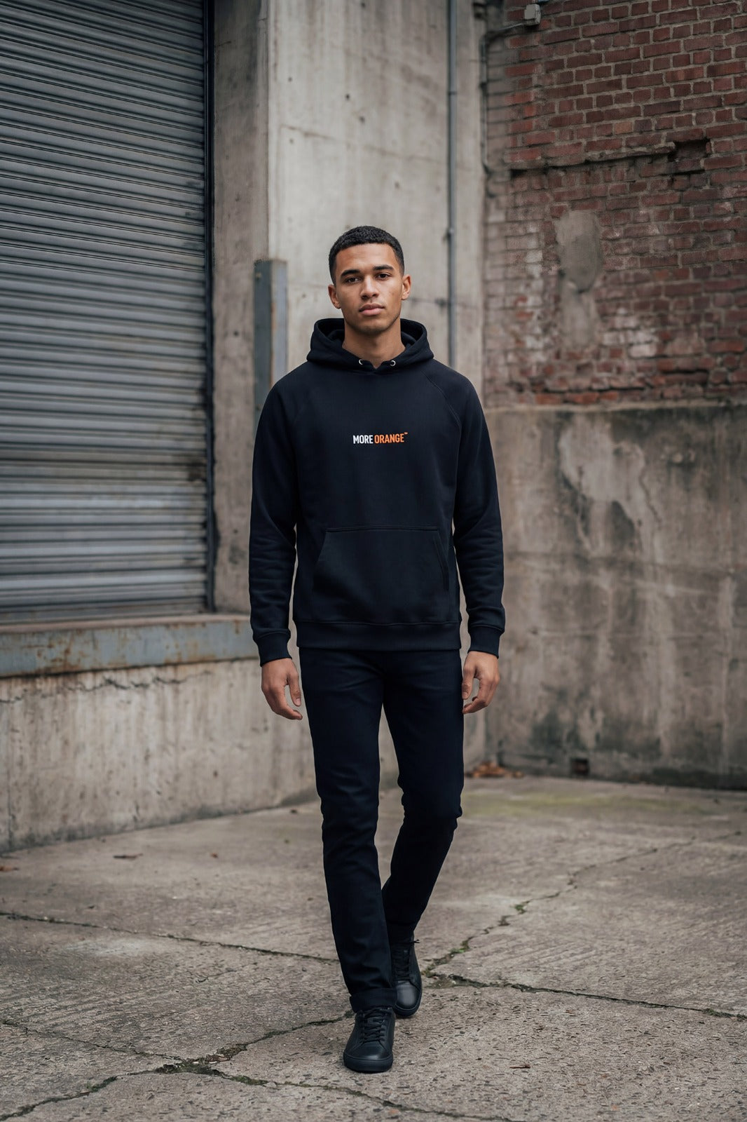 Front view of black MORE ORANGE™ hoodie worn by male model