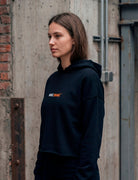 Half-side view of female model wearing black MORE ORANGE™ hoodie with clean design